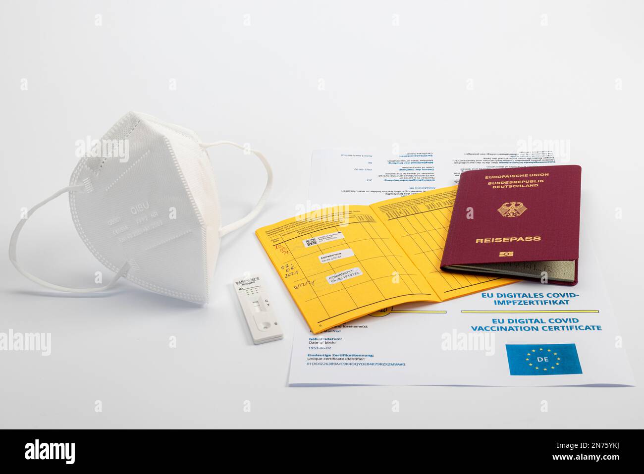 FFP2 mask, Rapid SARS-CoV-2 antigen test cassette with negative test result, Digital COVID certificate of the EU, Vaccination card with registration of the last Corona vaccinations, Passport of the Federal Republic of Germany, white background, Stock Photo