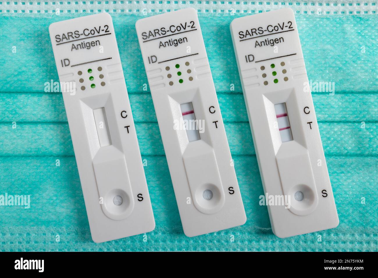 Medical Mouth Nasal Protective Mask, three Rapid SARS-CoV-2 Antigen Test Cassettes, one new antigen test cassette and two used ones, with one negative and one positive test result, Stock Photo