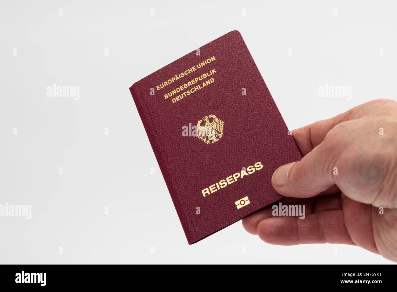 Male hand holding passport of Federal Republic of Germany, white background, Stock Photo