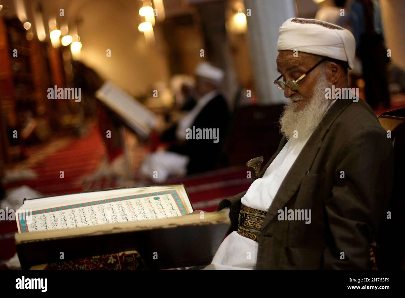 An elderly man reads verses of the Quran, Islam's holy book, on the ...