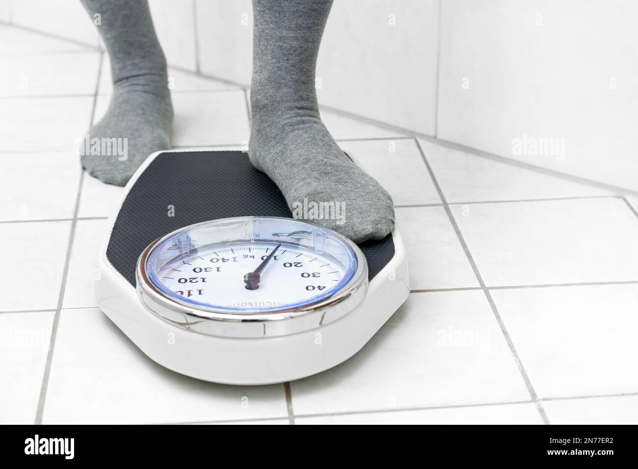 https://c8.alamy.com/comp/2N77ER2/feet-in-socks-stepping-on-a-personal-scale-on-the-tiled-bathroom-floor-to-measure-the-body-weight-copy-space-selected-focus-2N77ER2.jpg