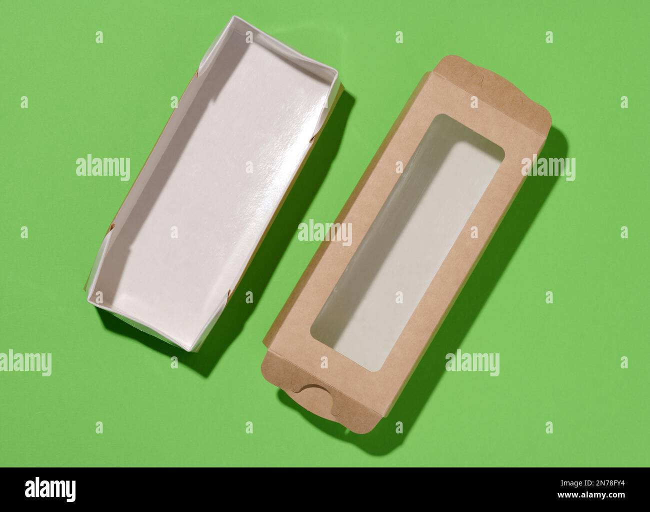 Rectangular cardboard box with a transparent plastic lid on a green background, top view Stock Photo