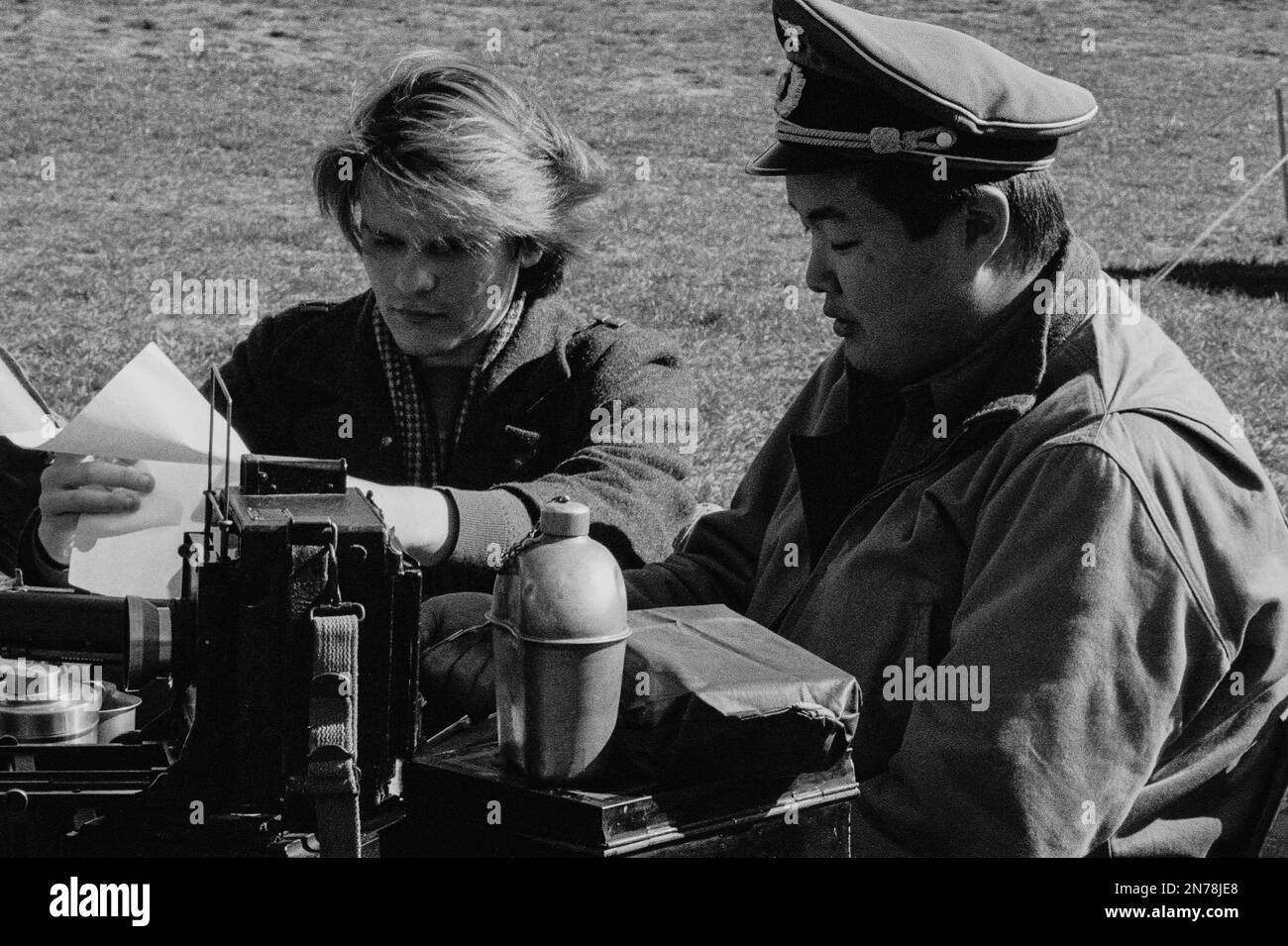 WWII German soldiers seated at a table with vintage camera equipment, canteen, and food during a reenactment at the American Heritage Museum. The imag Stock Photo