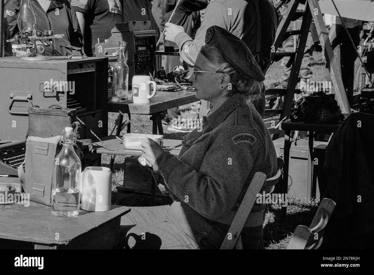 A WWII female reenactor sits a secretary desk under a tent at the American Heritage Museum. The image was captured on analog black and white film. Hud Stock Photo