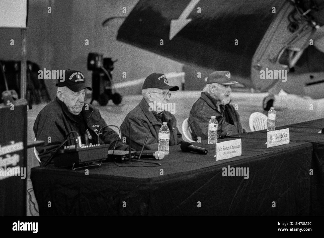 A group of WWII veterans speak to an audience in the hanger at the American Heritage Museum. The image was captured on analog black and white film. Hu Stock Photo