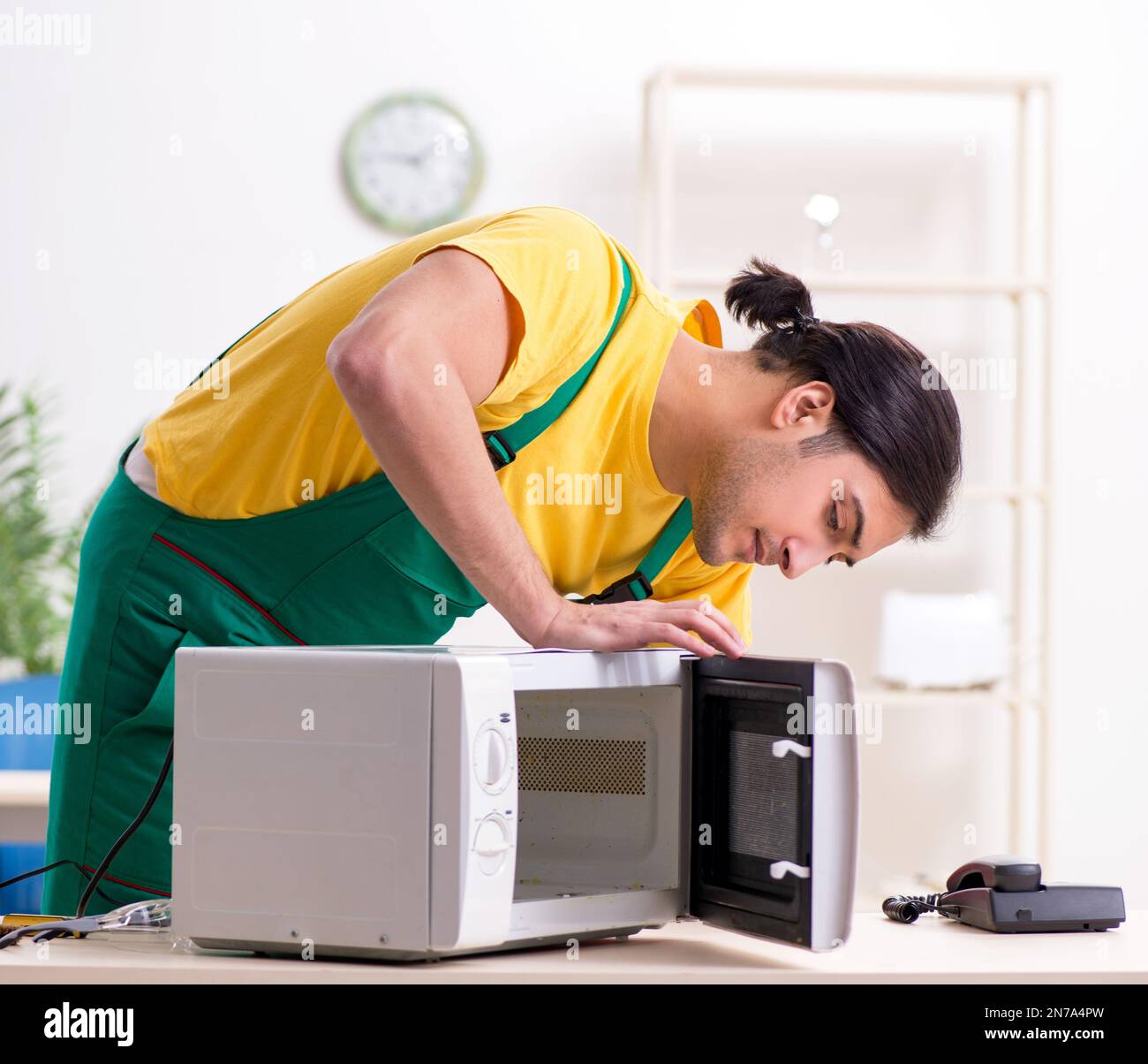 The young repairman repairing microwave in service centre Stock Photo