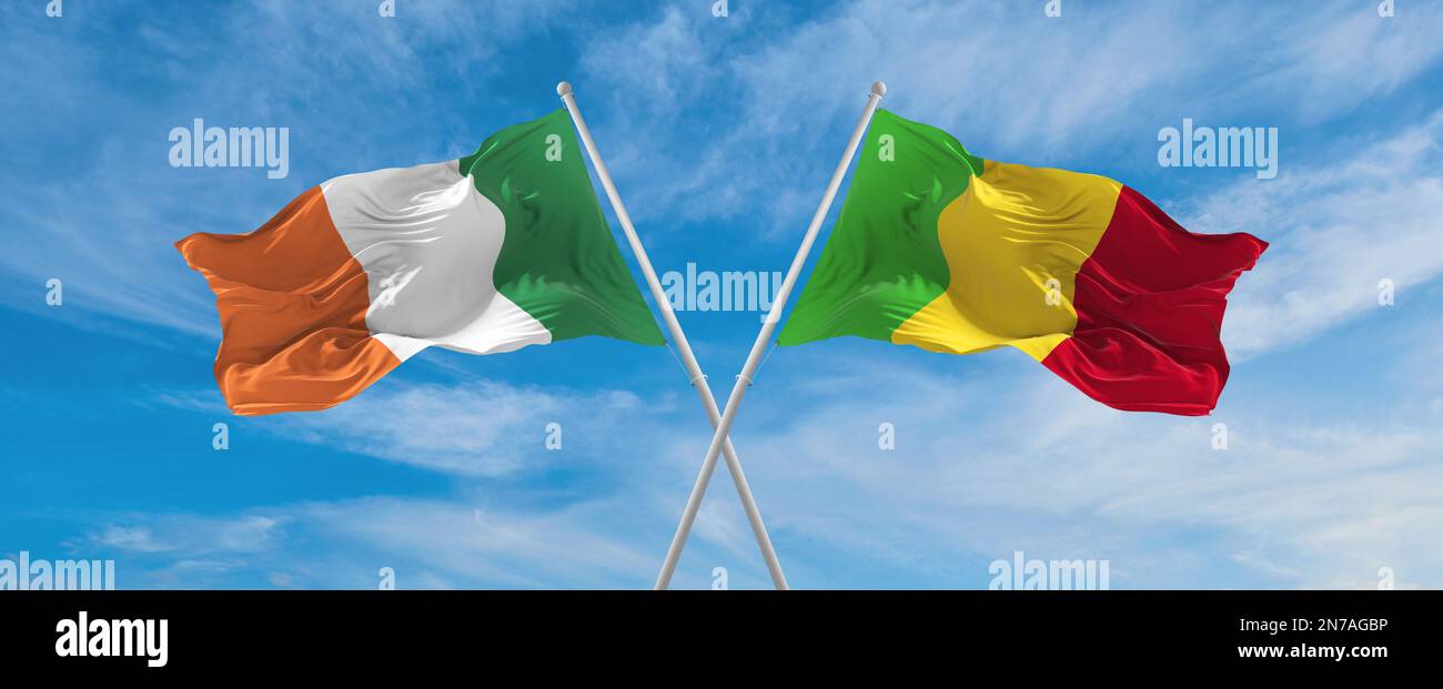 two crossed flags Mali and Ireland waving in wind at cloudy sky ...