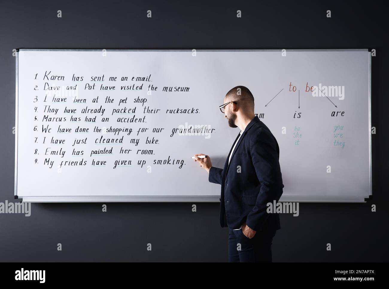 English teacher writing on whiteboard at lesson Stock Photo Alamy