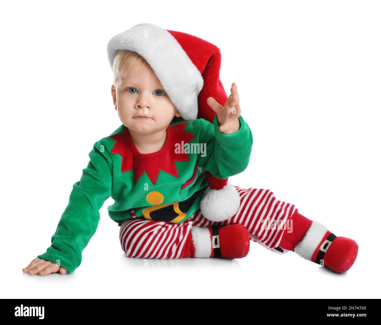 Cute baby in Santa's elf clothes sitting on white background. Christmas