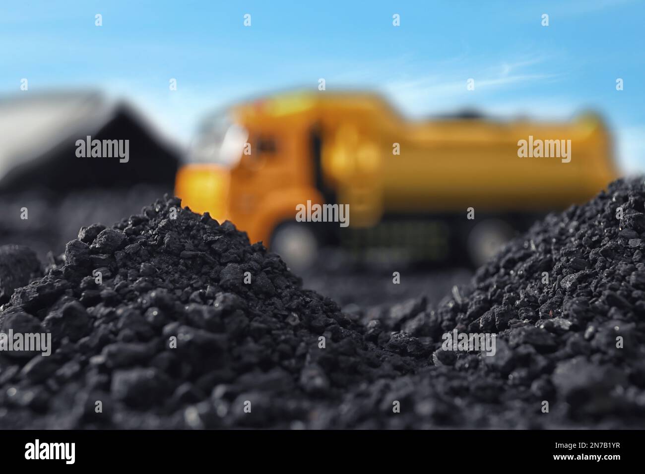 Piles of coal and blurred yellow truck on background, closeup Stock Photo