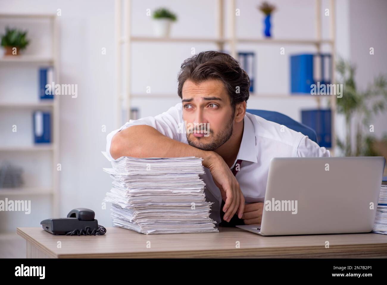 Young businessman employee and too much work at workplace Stock Photo ...