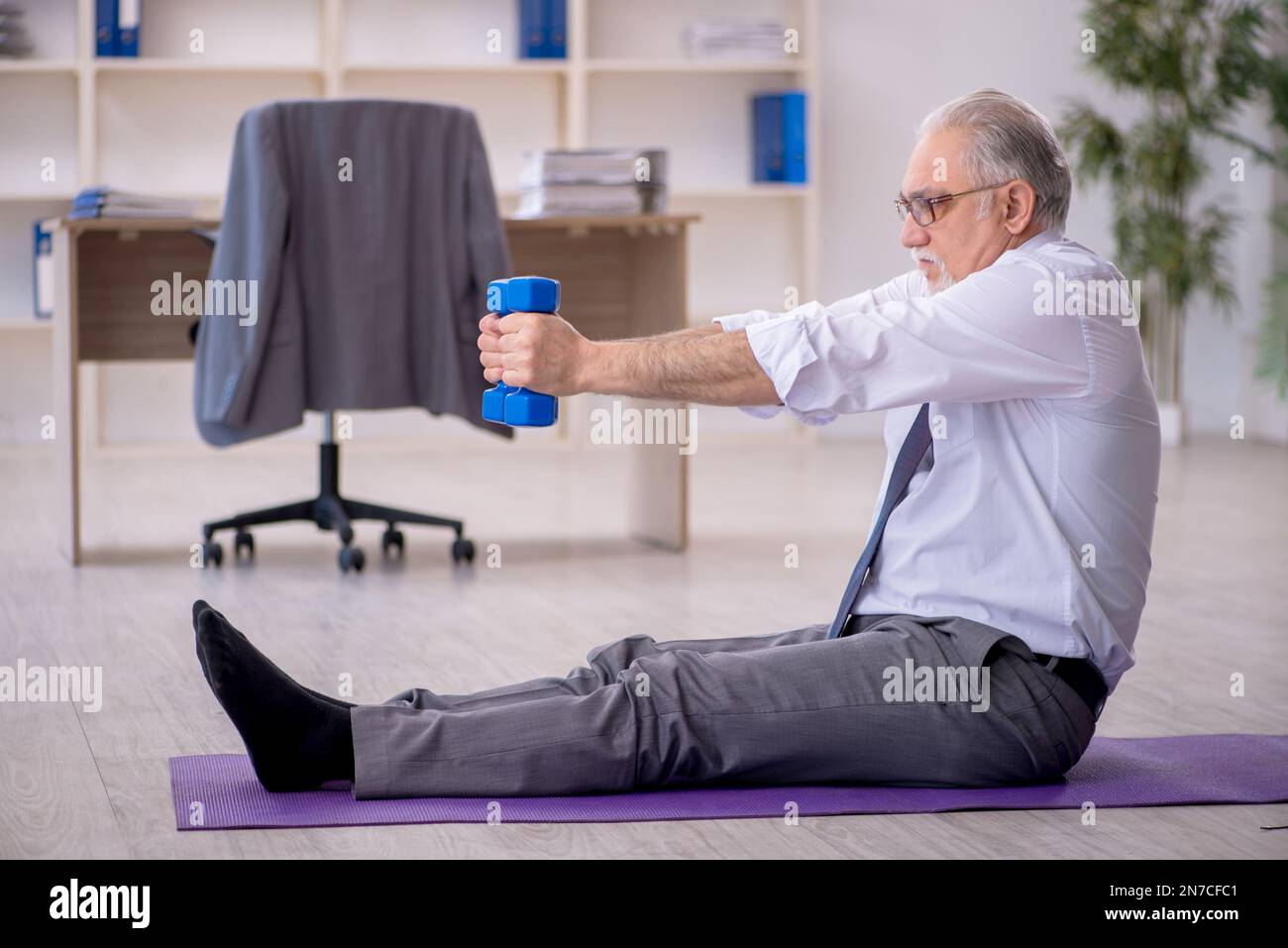 Old employee doing sport exercises during break Stock Photo
