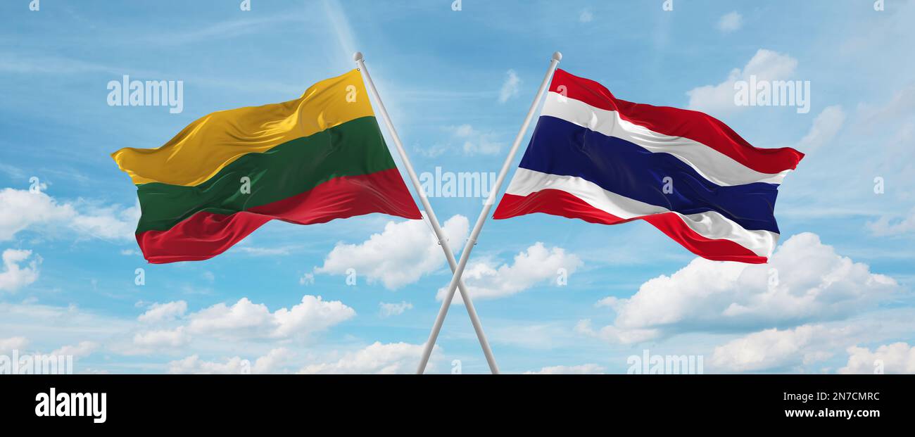two crossed flags thailand and Lithuania waving in wind at cloudy sky ...