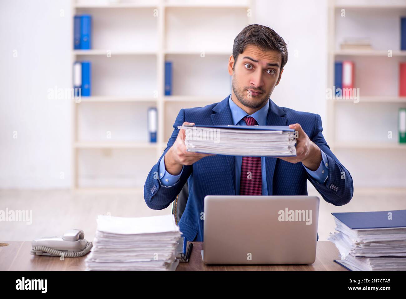 Young businessman employee and too much work at workplace Stock Photo ...