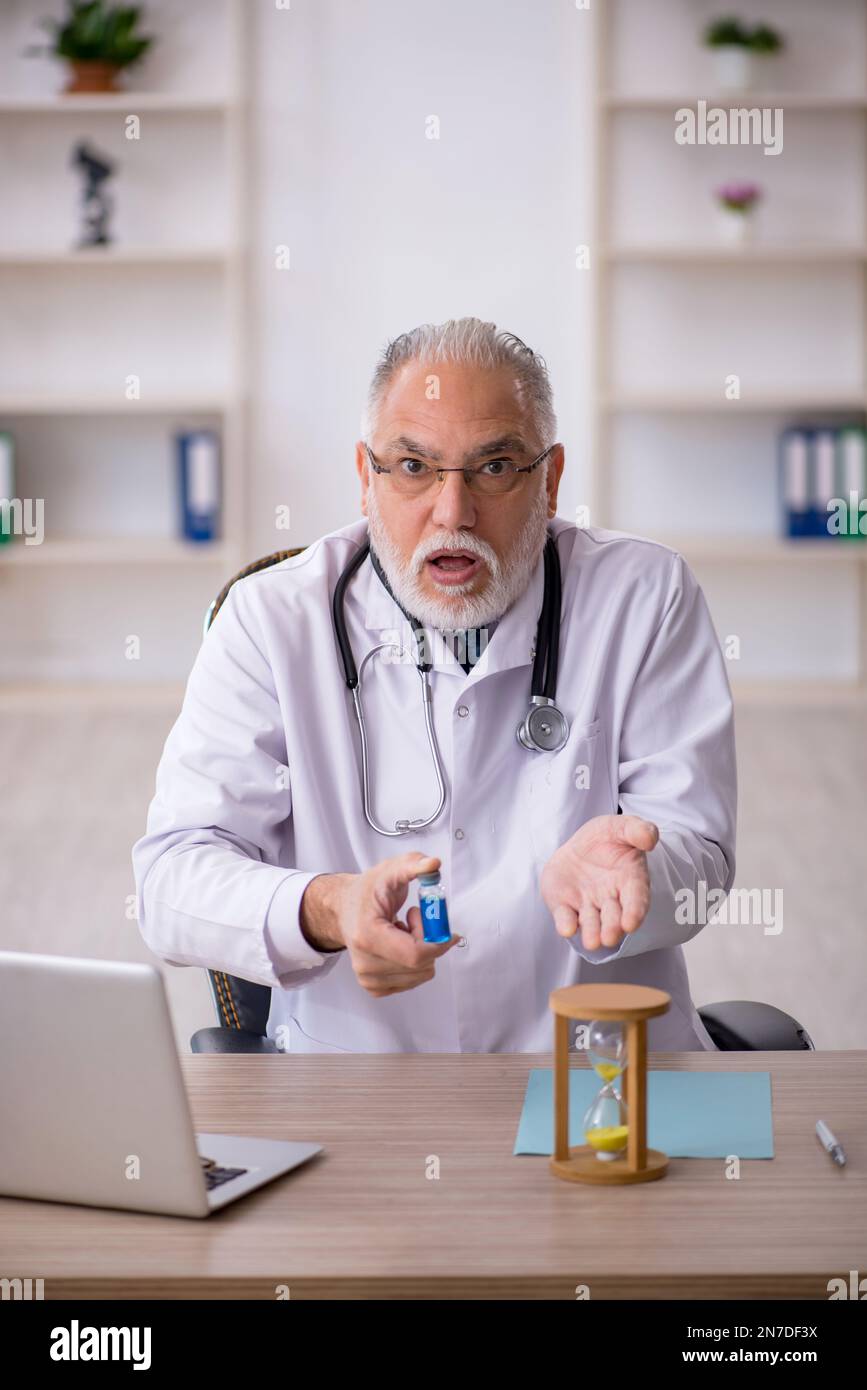 Old doctor in time management concept Stock Photo