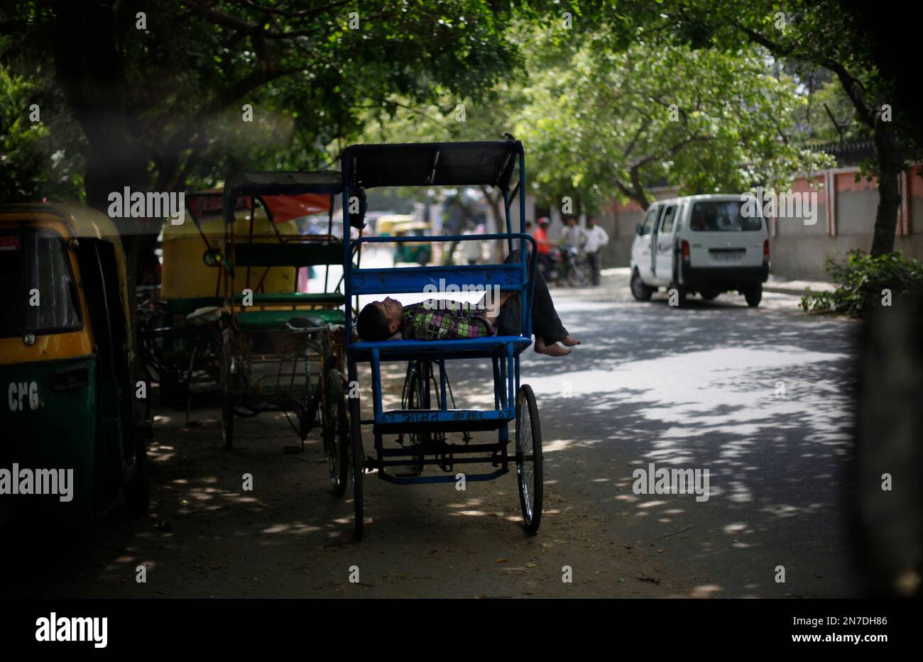 Altaf Rickshwa A rickshaw puller sleeps on his rickshaw in the shade of trees on a hot ...