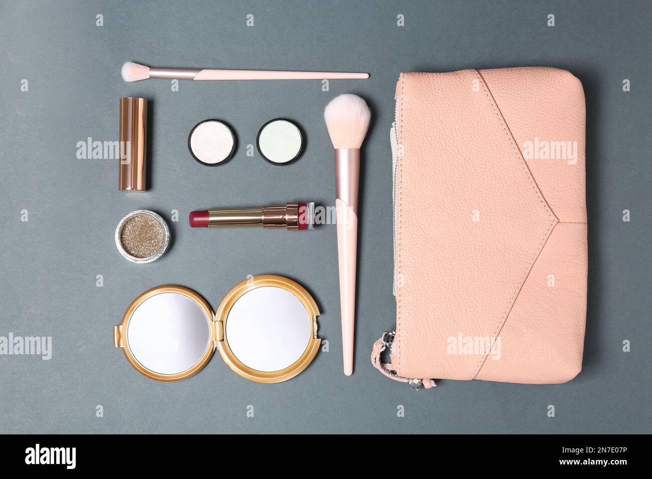 Cosmetic bag with makeup products on grey background, flat lay Stock Photo