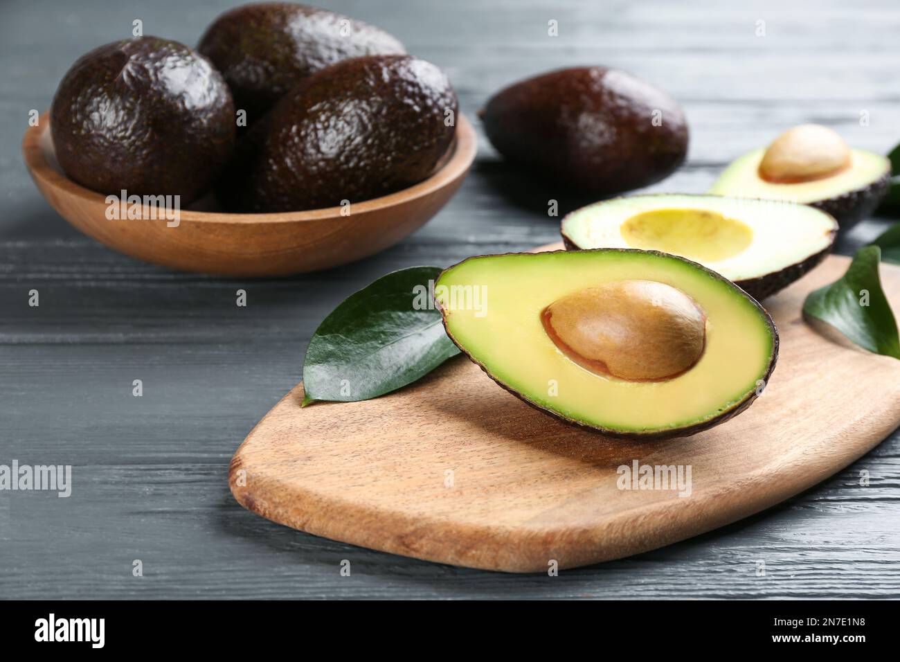 Whole and cut avocados on grey wooden table Stock Photo - Alamy