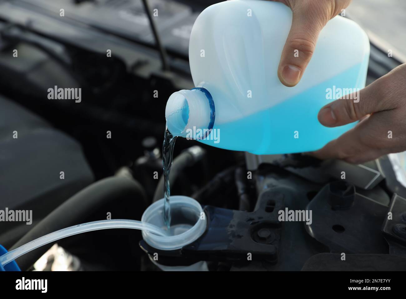 Man pouring antifreeze from plastic canister into windshield washer