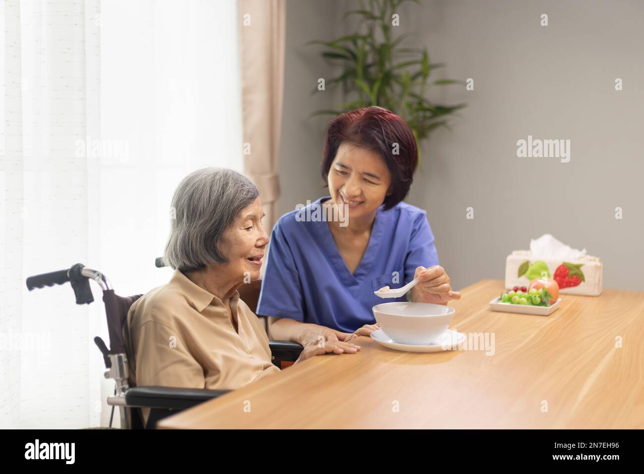 Caregiver feeding elderly asian woman with soup Stock Photo Alamy