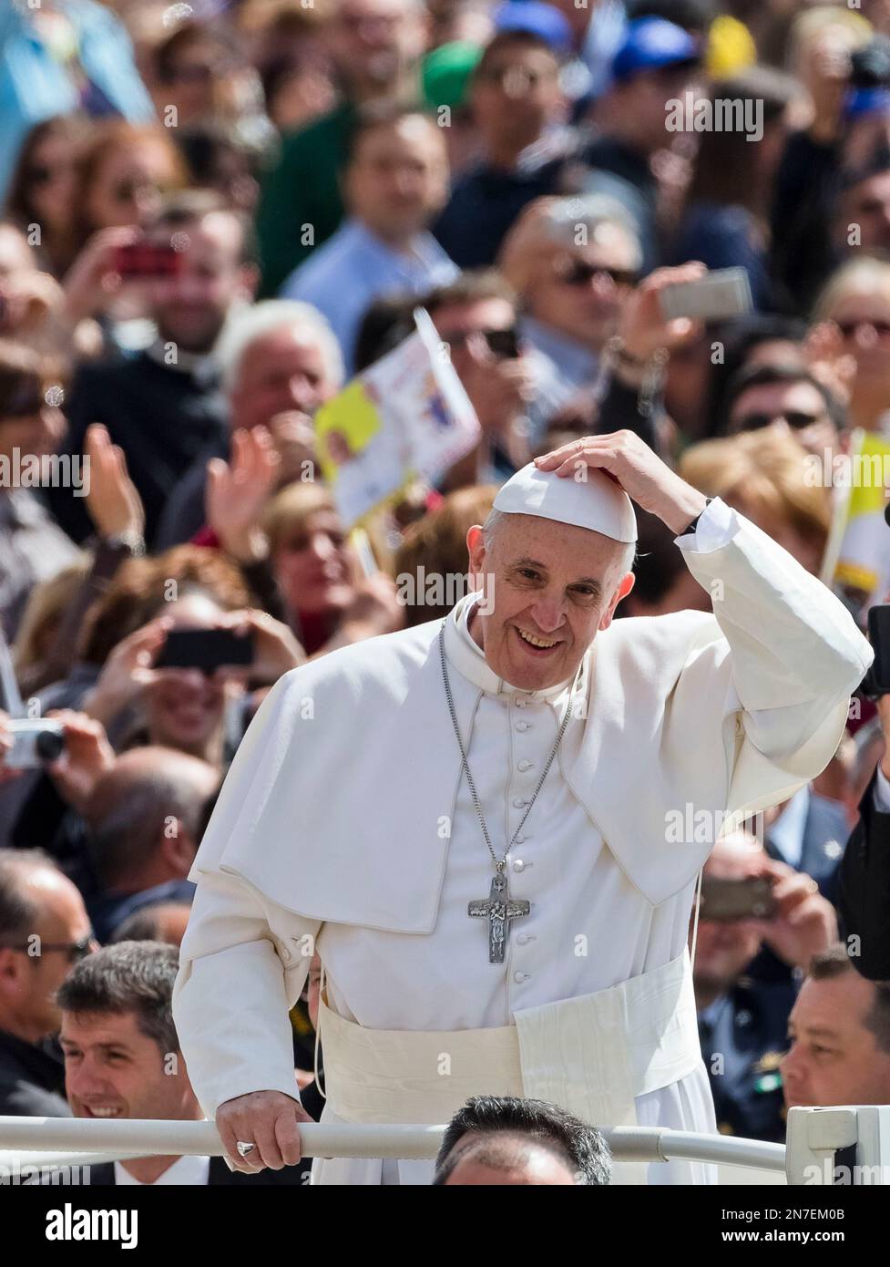 Pope Francis holds on his skull cap during a gust of wind while he ...