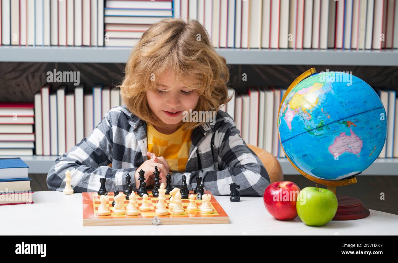 Chess school. Clever concentrated and thinking child playing chess. Child boy developing chess strategy, playing board game. Stock Photo