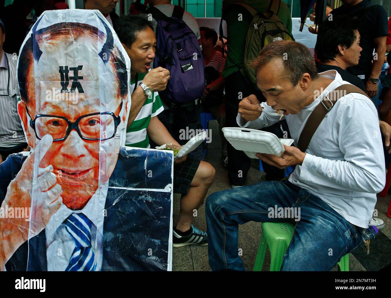 Container workers eat lunch next to a defaced portrait of Hong Kong