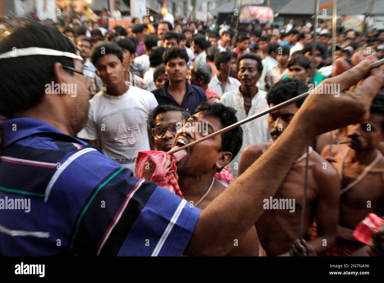 A Hindu devotee gets a metal rod pierced through his tongue as part of  performing a ritual during the Shiva Gajan festival in Bainan, West Bengal  state, India, Sunday, April 14, 2013.
