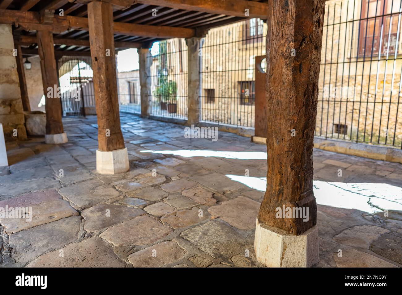 Arcades with very old wooden columns and cobbled floor in the medieval ...
