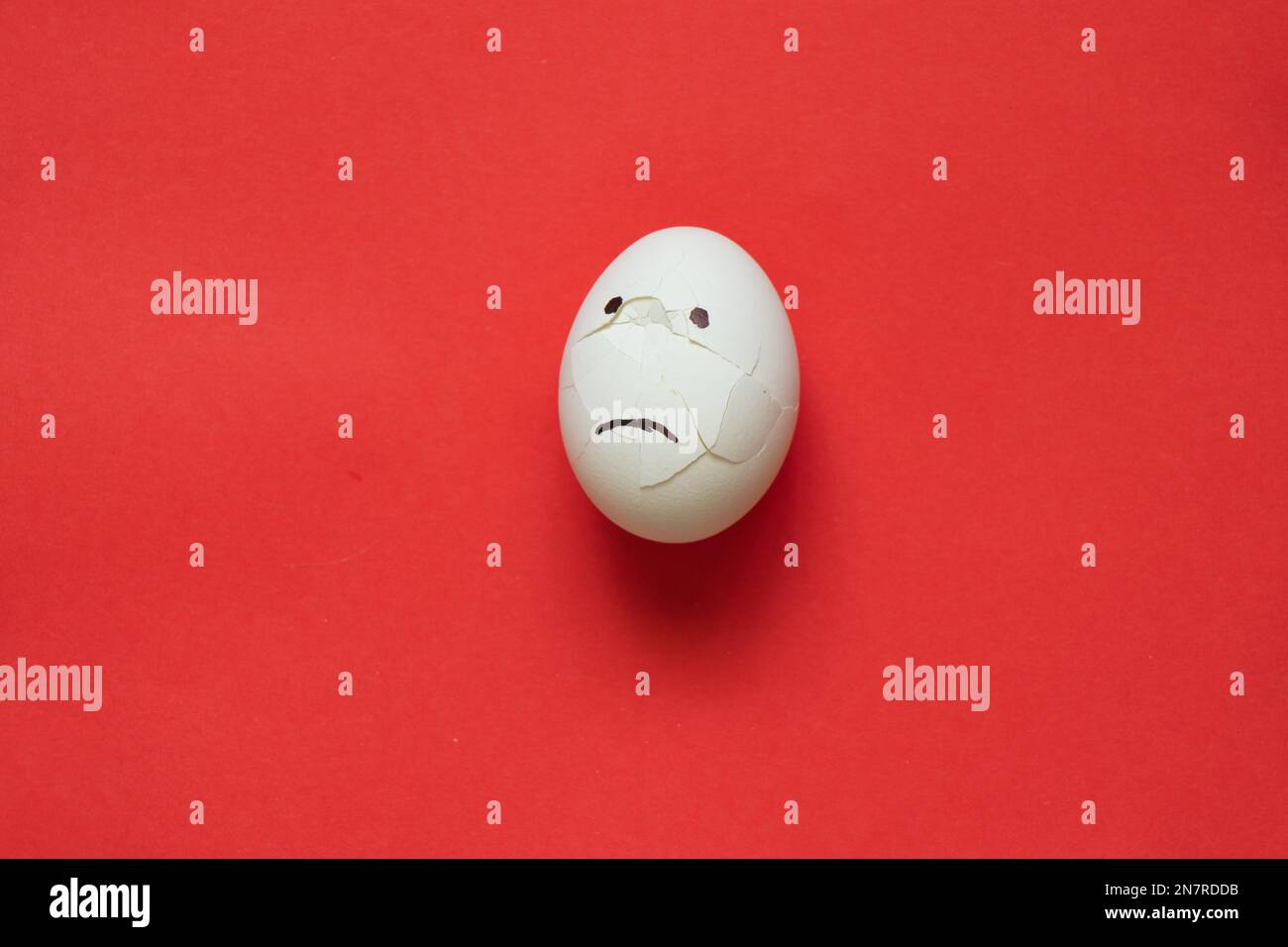 broken sad white chicken egg on a red Stock Photo