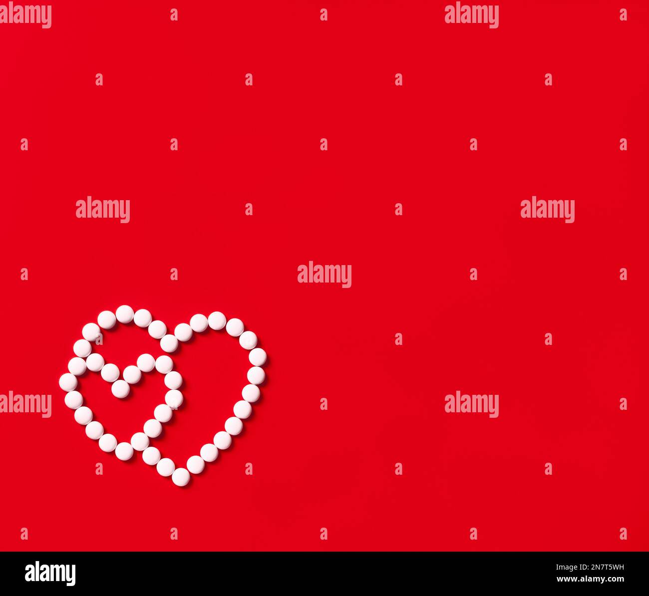 two hearts made of round white pills on a red background Stock Photo