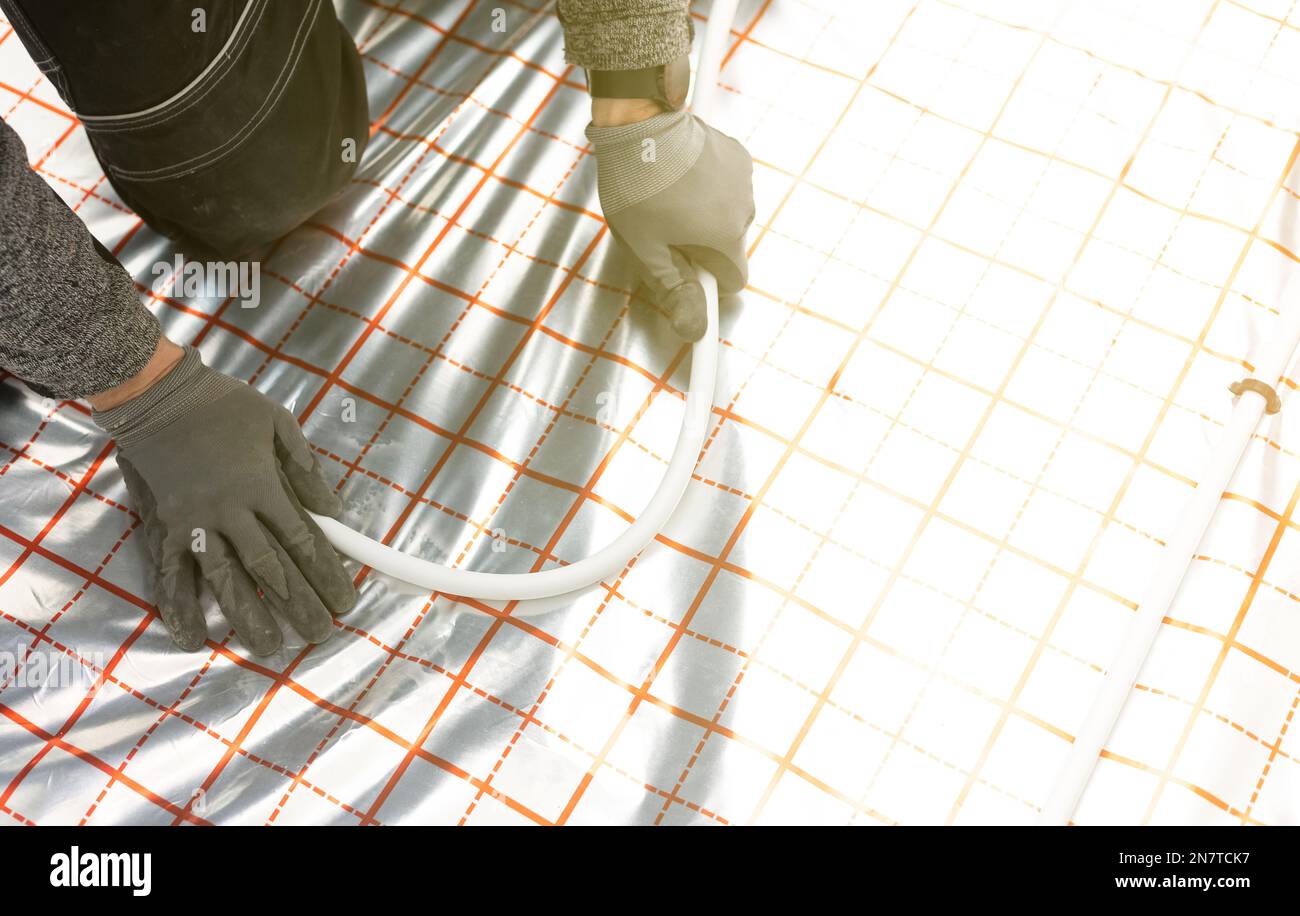 Worker installing underfloor heating system, water heating on the new