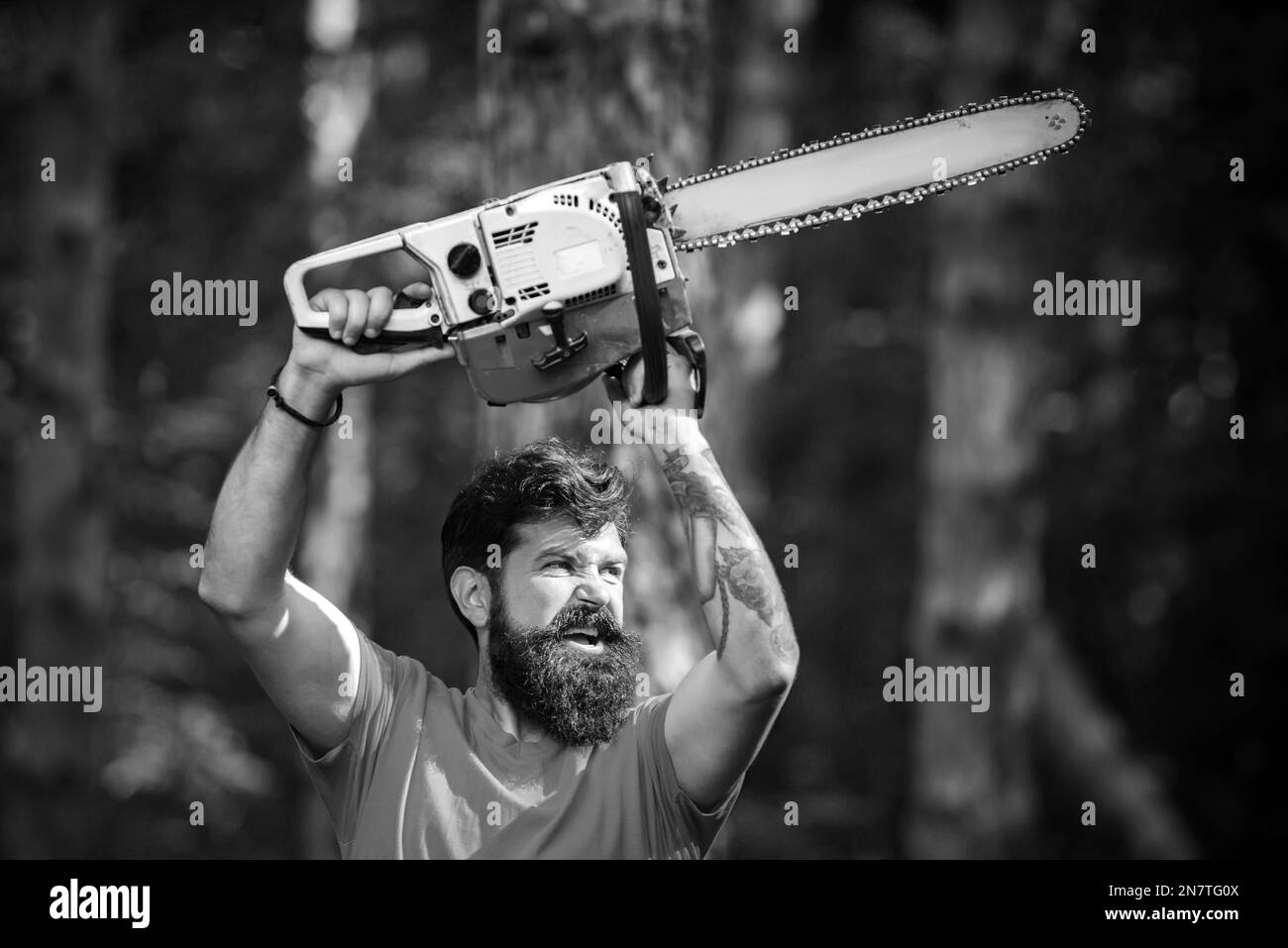 Lumberjack in the woods with chainsaw axe. Handsome young man with axe