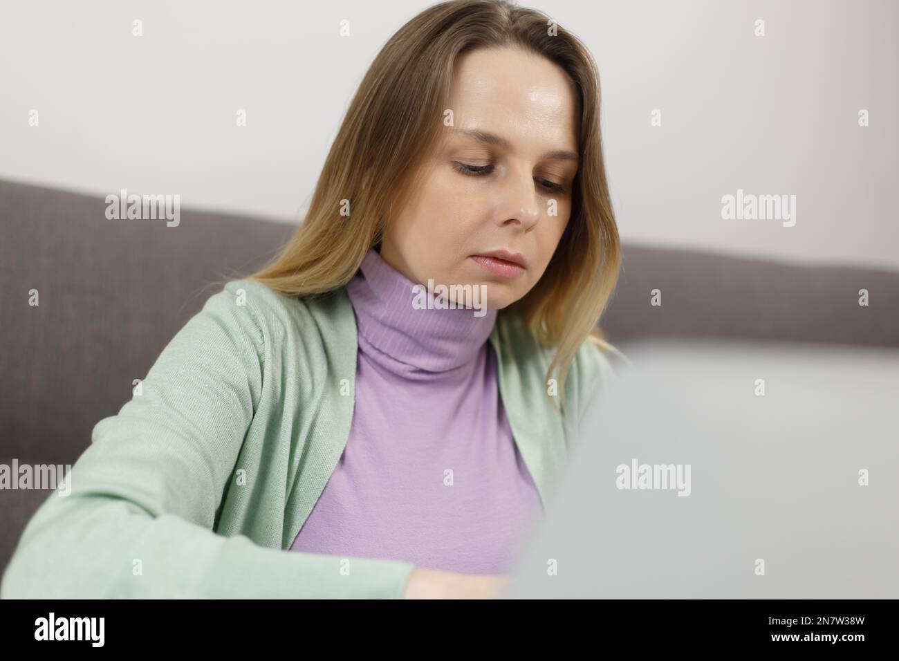 Focused white woman working on computer at home. Serious adult female person doing distant work online Stock Photo