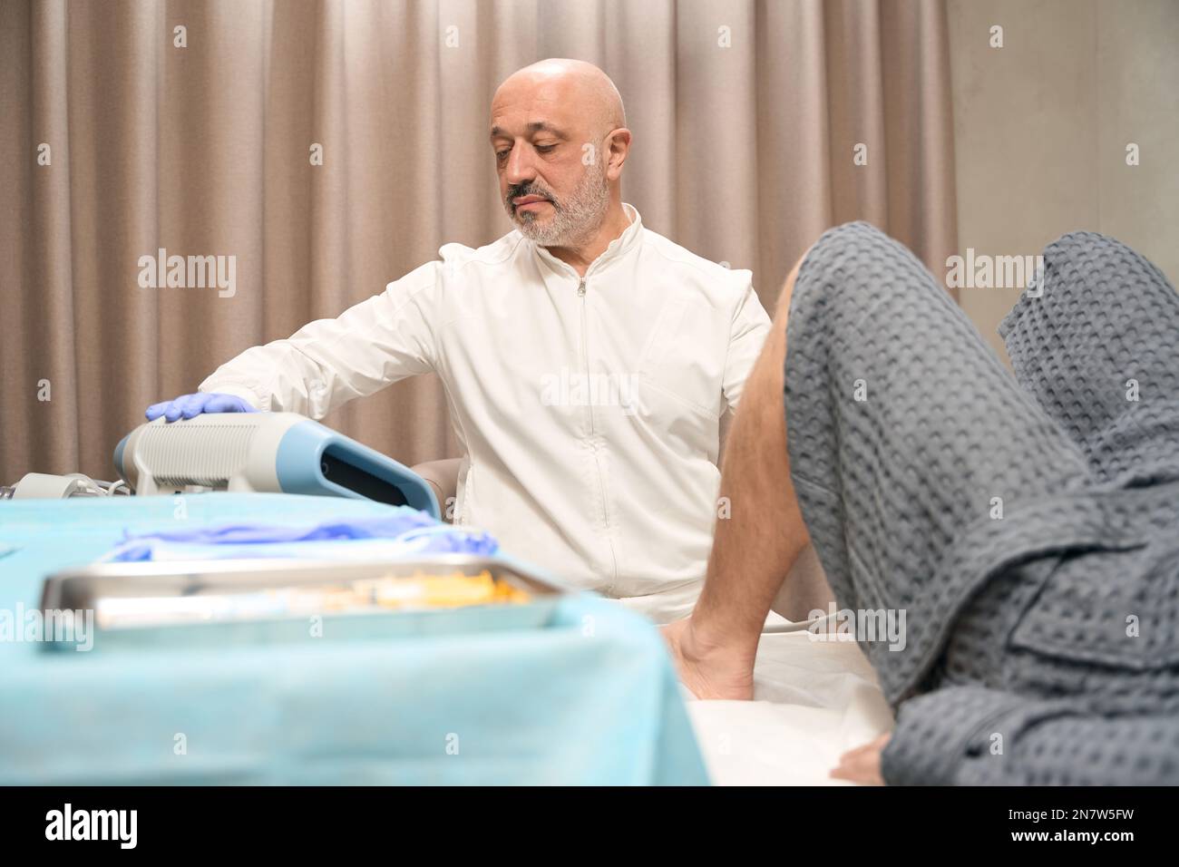 Intelligent doctor is using shock wave technology in the private clinic Stock Photo