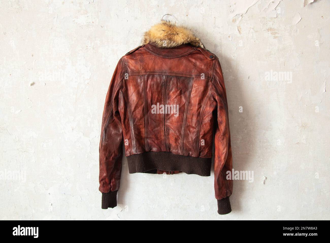 red fur leather winter women jacket hanging on a hanger on a white wall indoors Stock Photo