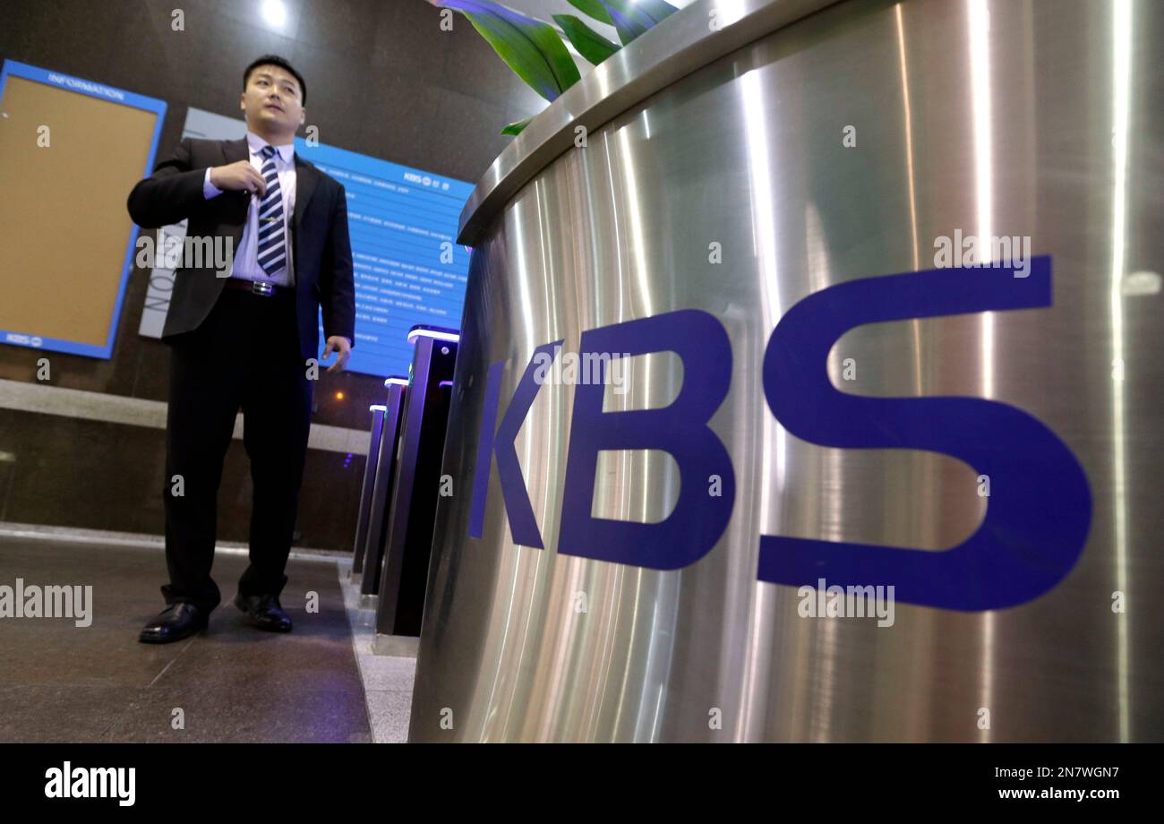 A security guard stands near a logo of Korean Broadcasting System at