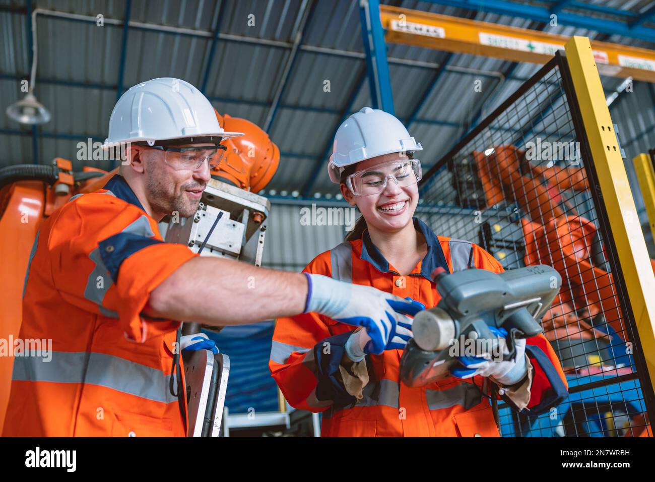 engineer team worker working program robot arm assembly machine in modern metal heavy industry factory Stock Photo