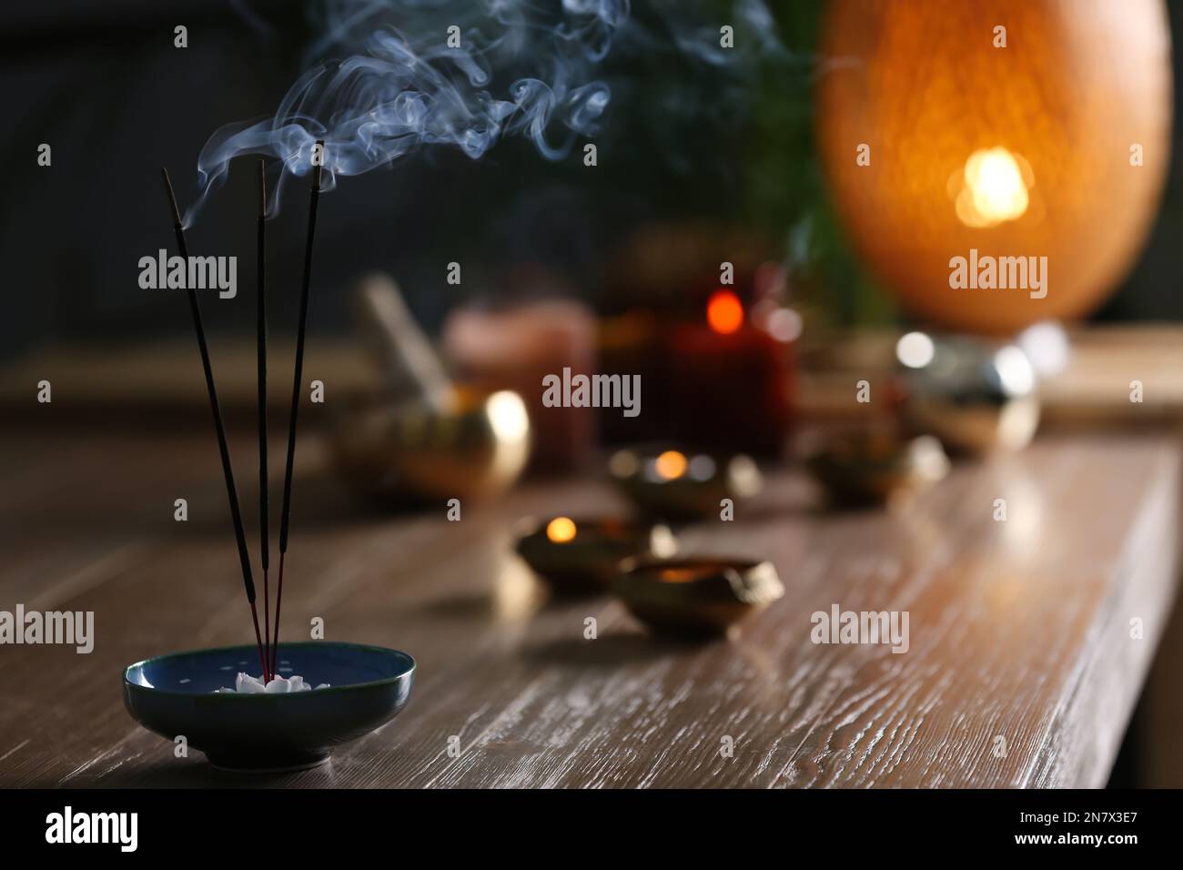 Incense sticks smoldering on wooden table in room. Space for text Stock ...