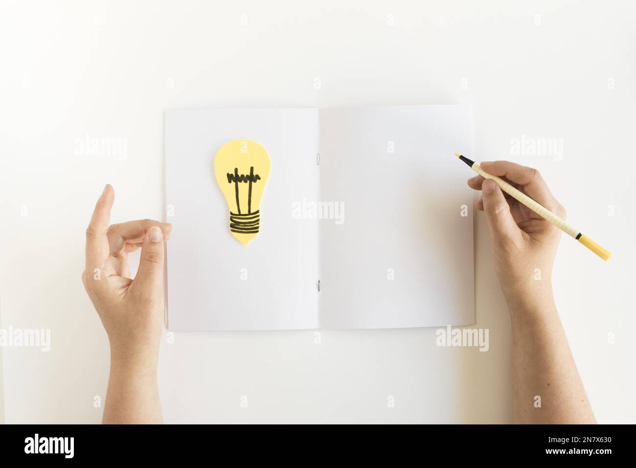 high angle view person s hand writing card with light bulb Stock Photo