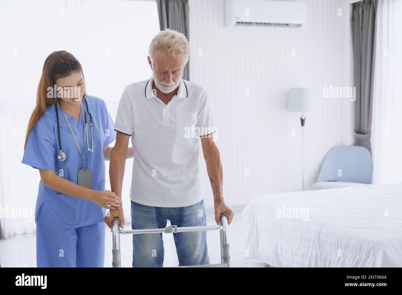 Physical therapist nurse supporting patient elderly senior old man practicing leg muscle recovery with walker equipment Stock Photo