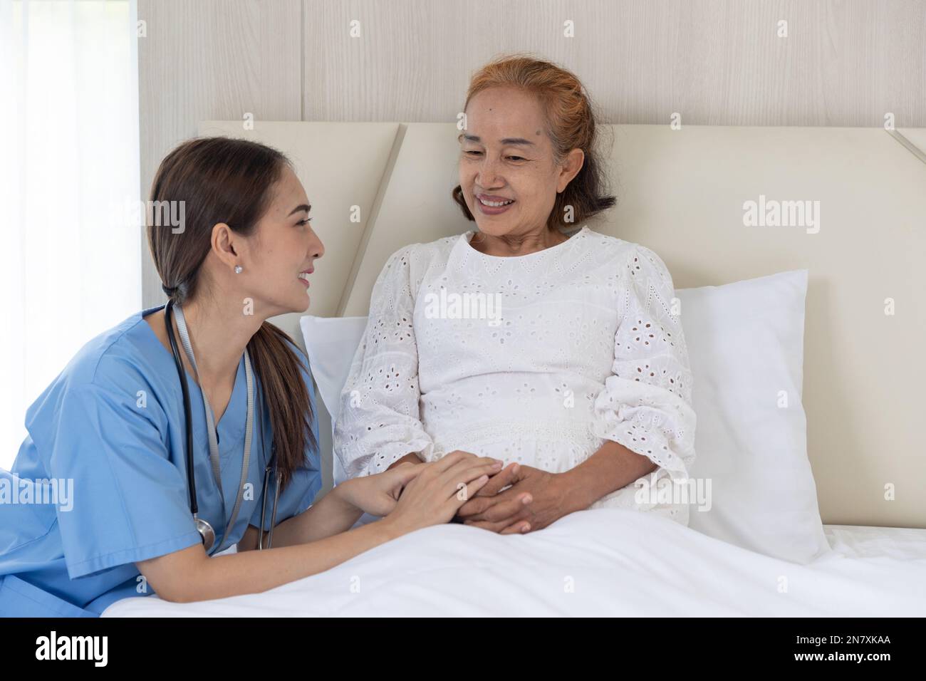 Nurse take care patient elderly senior woman talking consolation recovery on bed at home Stock Photo