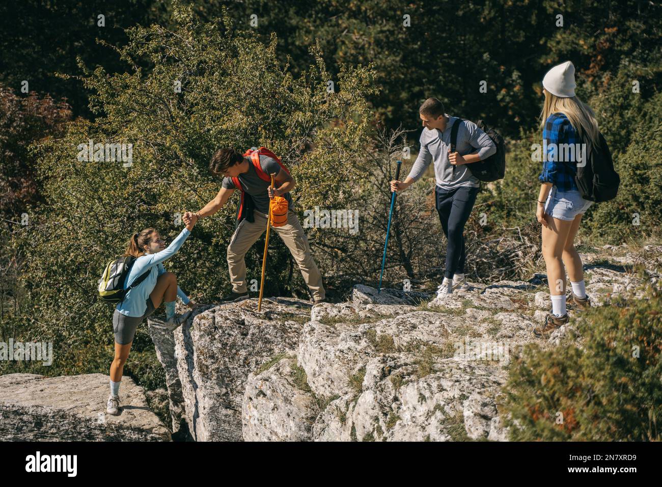 Friends On The Rocks HIker helping his friend to get on the rock while standing with his ...