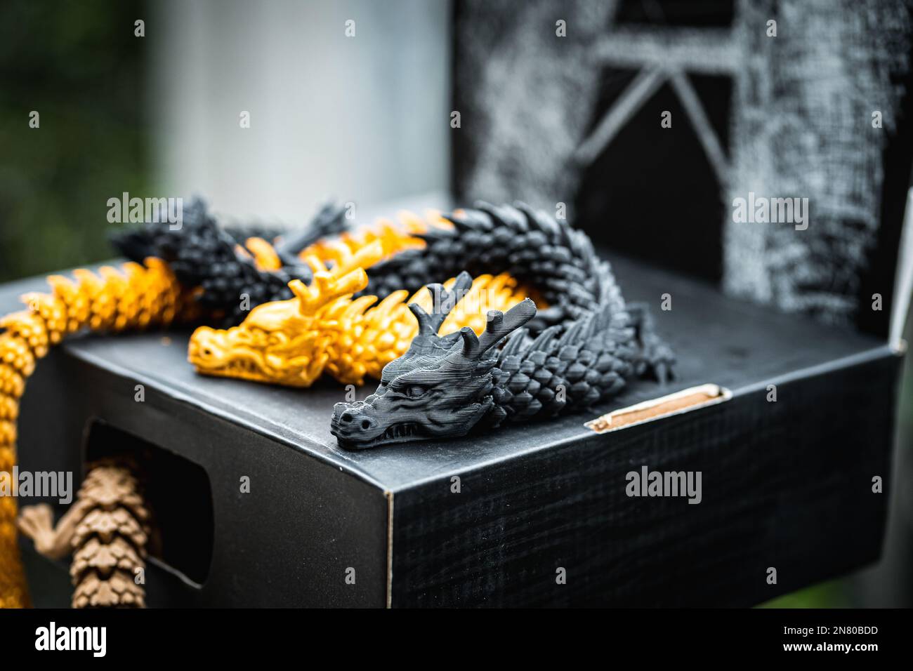 A closeup of 3D printed dragons in gold and black Stock Photo