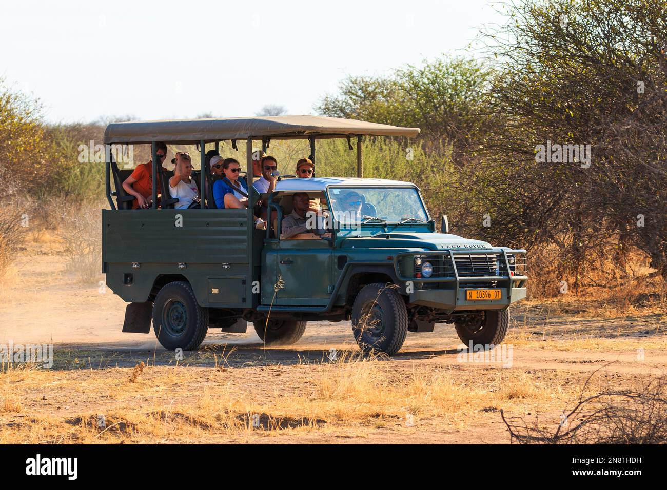 Waterber Plateau National Park, Namibia - 08 October 2018: Tourists viewing game from an open safari vehicle. Sunset over the savannah. Stock Photo