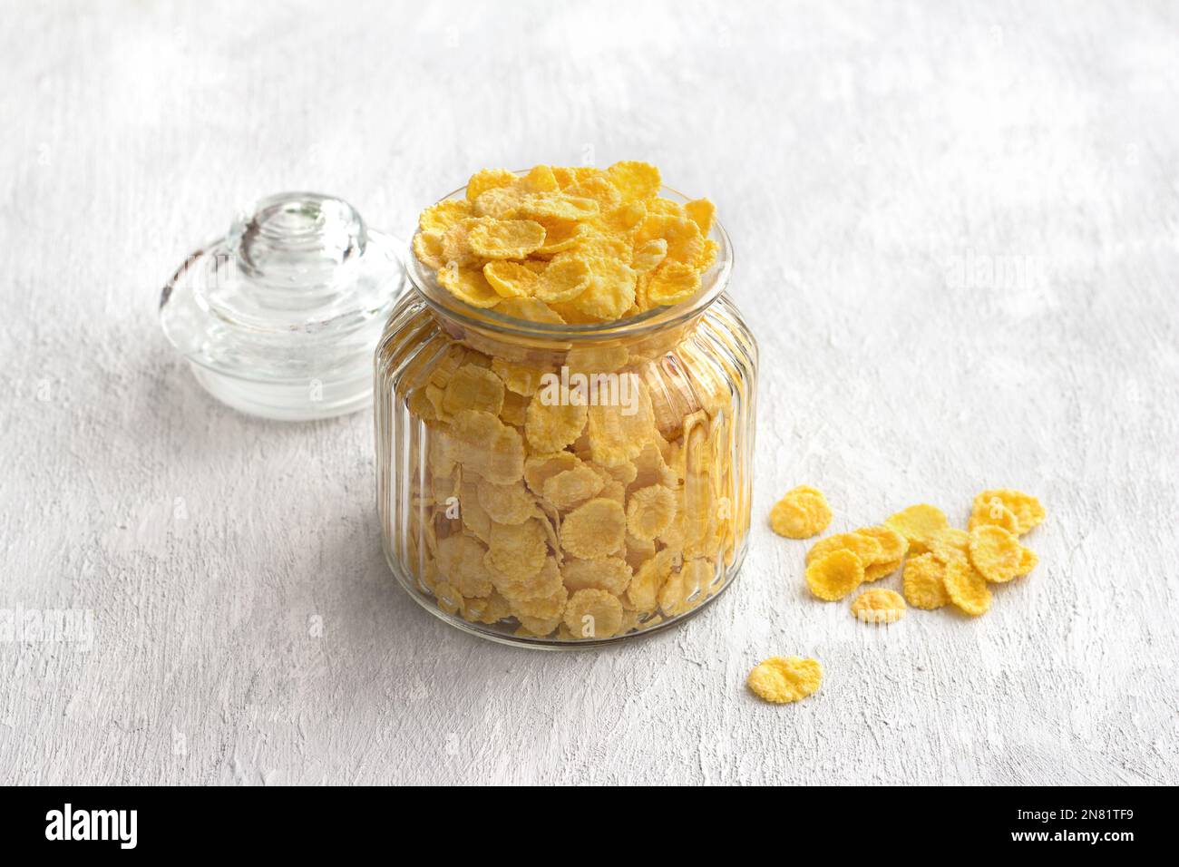 Sweet crunchy cornflakes in a glass jar on a gray textured background. Fast tasty breakfast, free space, horizontal Stock Photo