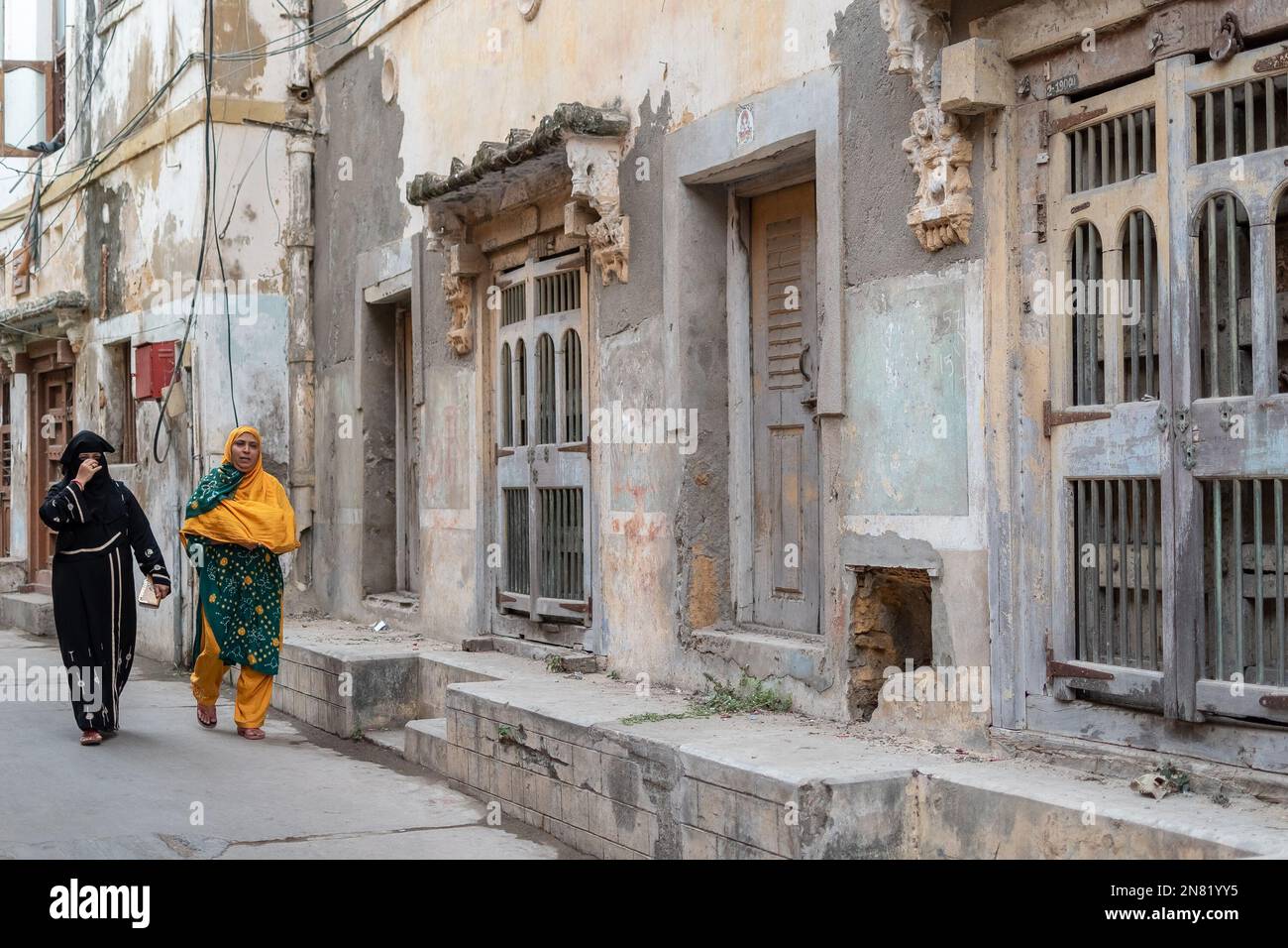 Diu, India - December 2018: Two Indian women walking past old vintage houses in the island town of Diu. Stock Photo