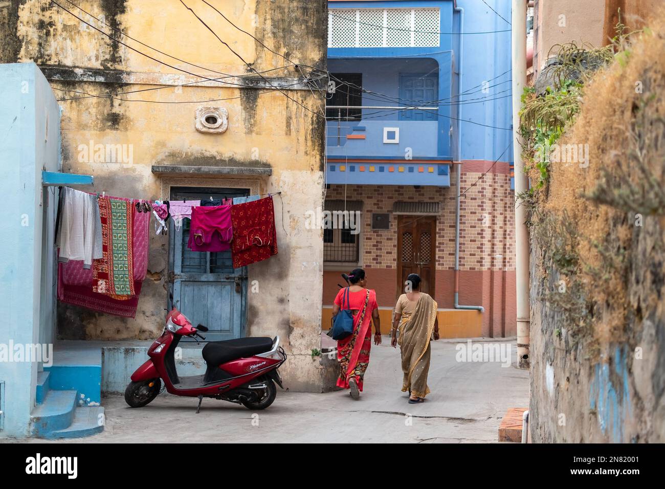 Diu, India - December 2018: Rear view of two women walking through a narrow alley in an old neighbourhood in the town of Diu. Stock Photo