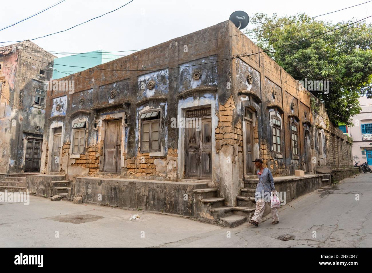 Diu, India - December 2018: A man walking past an old dilapidated Portuguese era building in the island town of Diu. Stock Photo