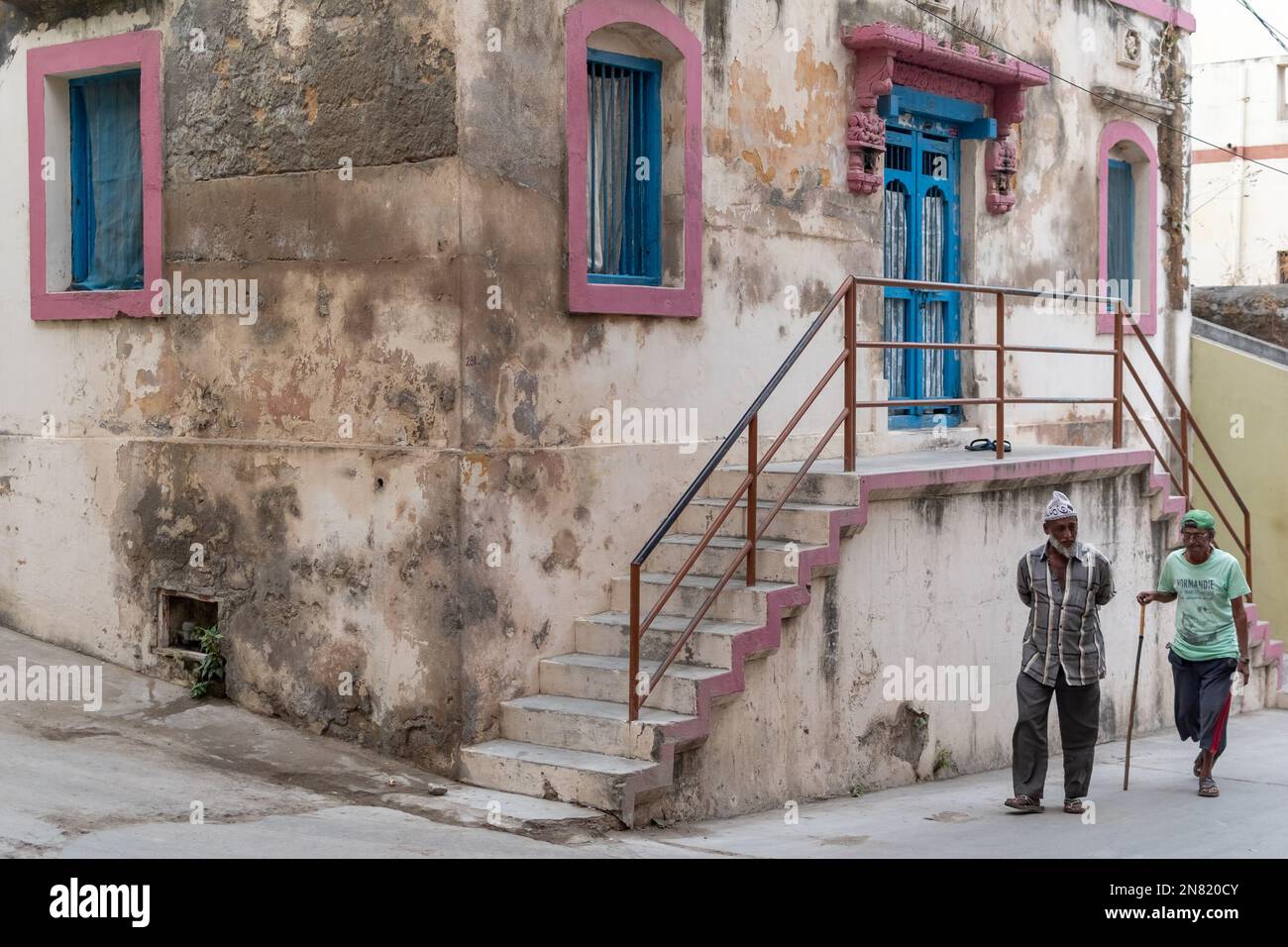 Diu, India - December 2018: Two old men walking past an old Portuguese era house in the streets of Diu. Stock Photo